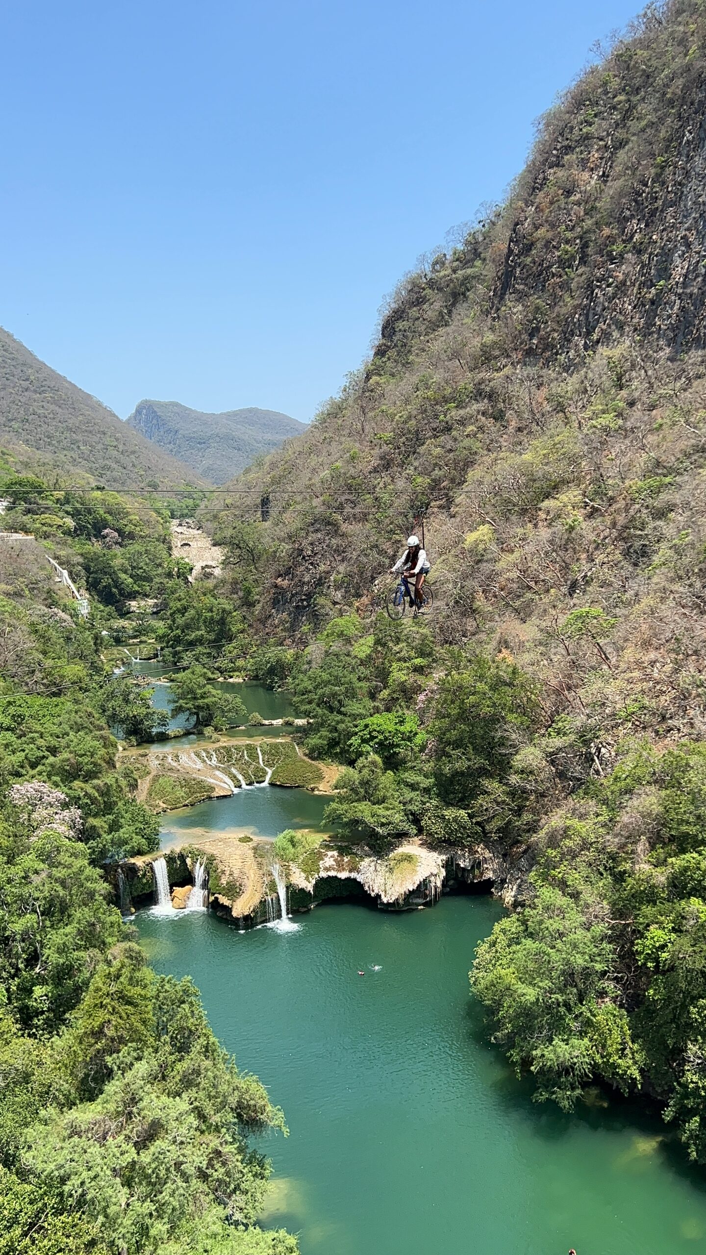 A girl riding a zipline bike also known as sky bike in one of the best waterfalls in Mexico.