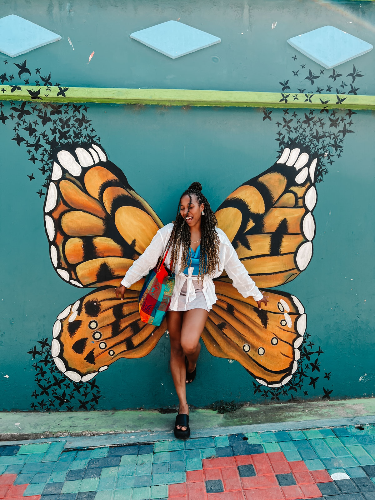 Woman standing in front of a butterfly mural in San Juan Laguna, Lake Atitlan Guatemala