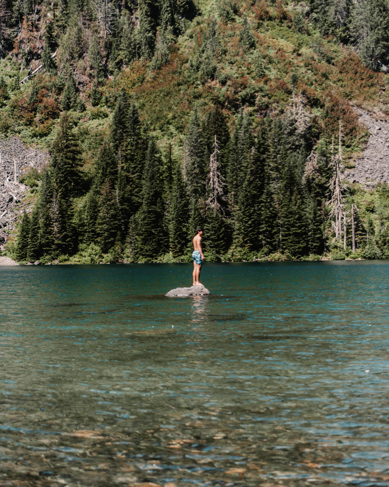 a man standing on a rock in the middle of alpine lake 22, Washington sate. 